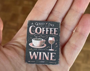 May include: A small, rectangular sign with the text "A GOOD DAY starts with COFFEE and ends with WINE 1992." The sign features a coffee cup, a wine glass, and decorative flourishes, all in a vintage style with a black background and pink lettering.