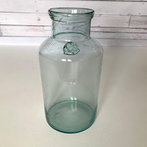 Könnte beinhalten: Ein klares Glasgefäß mit einer strukturierten Oberfläche und einem abgerundeten Boden. Das Gefäß hat eine breite Öffnung und einen kleinen Rand um die Öffnung.