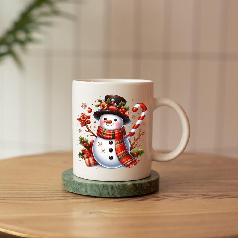 May include: White ceramic mug with a snowman design. The snowman is wearing a black top hat, red and green scarf, and holding a candy cane.