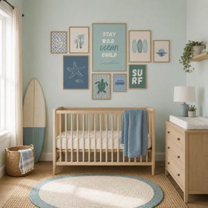 May include: A nursery decorated in a coastal style. The room includes a wooden cot, chest of drawers, and framed art with ocean-themed illustrations. A surfboard leans against the wall, and a round rug is on the floor. The art includes the text "Stay Wild Ocean Child."