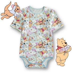 Puede incluir: Un body de bebé azul claro con un estampado repetido de Winnie the Pooh y sus amigos. El body de manga corta tiene ribetes azul claro y cuello redondo. También se ven ilustraciones de dibujos animados de Roo y Winnie the Pooh.