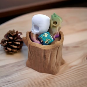 May include: A wooden tree stump shaped dice holder with a white skull, a green and purple dragon, and a teal and gold dice with the number 60 on it.