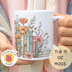 May include: White ceramic mug with a floral design featuring stacked books, flowers, and leaves. The mug is 11 or 15 ounces and has a handle. The mug is held by a hand.