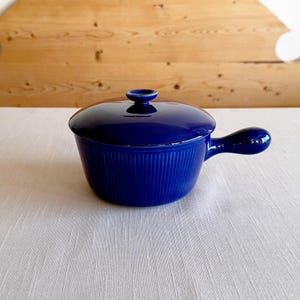 以下が含まれることがあります： 蓋と取っ手付きの青いセラミック製の食器。食器はリブ模様です。