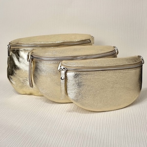 May include: Three gold-coloured leather fanny packs of different sizes. The fanny packs have a zipper closure and a silver buckle.