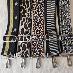 May include: Five different fabric straps with silver swivel clasps. The straps are black with gold stars, leopard print, black and white chevron, and black and white paisley.