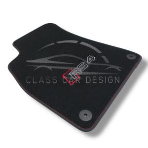 Könnte beinhalten: Schwarze Auto-Fußmatte mit roten Nähten und dem Text "RS4" in Rot. Die Matte trägt auch den Text "CLASS CAR DESIGN" in Weiß. Zwei schwarze Befestigungselemente sind sichtbar.