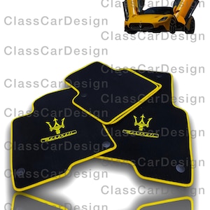 May include: Set of four black car floor mats with yellow edging and a Maserati logo embroidered in yellow.