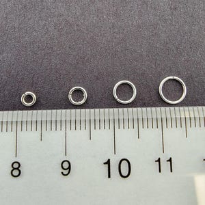 May include: Four silver jump rings of different sizes, measured on a ruler with markings from 8 to 11.
