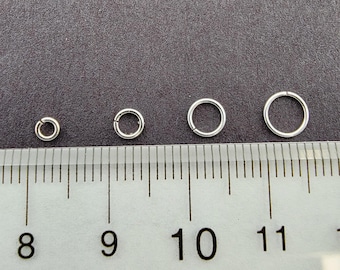 May include: Four silver jump rings of different sizes, measured on a ruler with markings from 8 to 11.