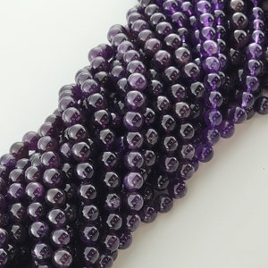 May include: A strand of round, purple amethyst beads. The beads are smooth and polished, and they have a slight shine.