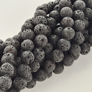 May include: A strand of black lava rock beads. The beads are round and have a rough, textured surface.