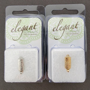May include: Two silver and gold metal end caps for jewelry making. The end caps are in clear plastic packaging with the words "elegant elements elite components" on the front.