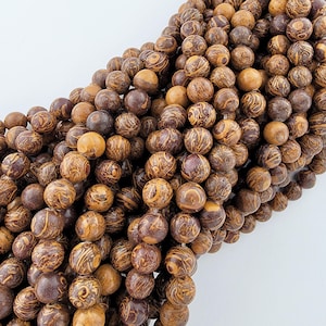 May include: A strand of brown and gold marbled round beads. The beads have a swirling pattern and are approximately 10mm in diameter.