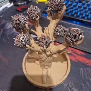 Könnte beinhalten: Ein 3D-gedruckter, baumförmiger Ringständer mit sechs Ringen. Die Ringe sind silberfarben mit roten Akzenten und haben ein stacheliges, strukturiertes Design. Der Baum ist braun und hat eine runde Basis.
