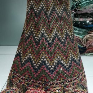 May include: A black skirt with a geometric pattern of colourful sequins. The skirt has a border of gold and black embroidery.