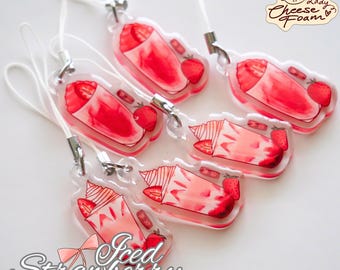 May include: Clear acrylic charms featuring a watercolor design of iced strawberry drinks. Each charm has a white cord and silver-colored hardware. The charms are in various shapes, with the words "Iced Strawberry" in a cursive font.