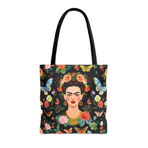 May include: A black tote bag with a floral and butterfly print featuring a portrait of Frida Kahlo. The bag has black straps.