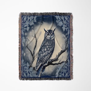 May include: A woven tapestry throw blanket featuring a blue and white owl perched on a branch. The owl is surrounded by a blue and white floral design.