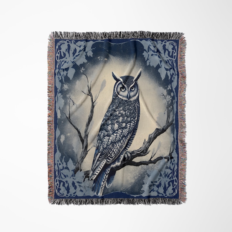 May include: A woven tapestry throw blanket featuring a blue and white owl perched on a branch. The owl is surrounded by a blue and white floral design.