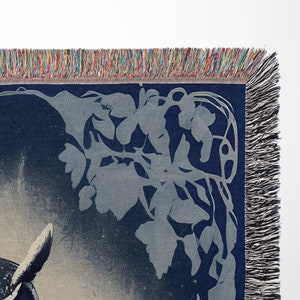 May include: A blue woven tapestry with a white owl design and a floral pattern in the corner. The tapestry has a fringe border.