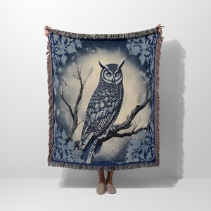 May include: A woven throw blanket featuring a blue and white owl perched on a branch. The owl is surrounded by a blue floral pattern.
