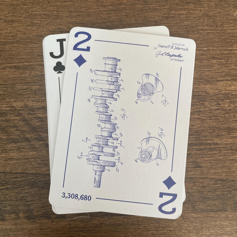 Two playing cards are displayed. The first card is a Jack of Clubs. The second card is a Two of Diamonds, featuring a blue engineering drawing of an engine component. The card also has the number '2' in the bottom right corner and the text '3,308,680' at the bottom. The top right corner has the text 'Everett & Sherrick BY J.L. Carpenter ATTORNEY'.