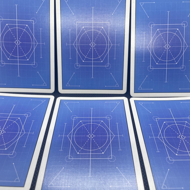 May include: A collection of playing cards with a blueprint design. Each card features a blue background with white geometric shapes, including circles, lines, and angles. The cards have white borders and a clean, modern aesthetic.