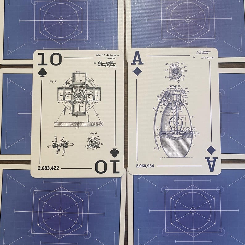 Ten of clubs and Ace of diamonds playing cards faced up. Ten shows a combustion engine engineering drawing and ace shows a grenade engineering drawing.