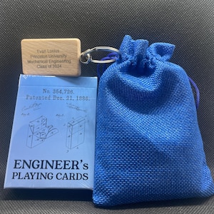 A blue drawstring baggy with a wooden keychain attached that reads "Evan Losious, Princeton University, Mechanical Engineering, Class of 2024". The wooden keychain is resting on an unopened deck of cards.