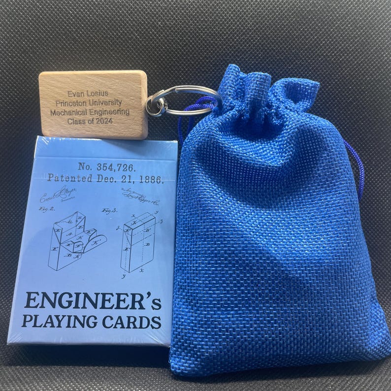 A blue drawstring baggy with a wooden keychain attached that reads "Evan Losious, Princeton University, Mechanical Engineering, Class of 2024". The wooden keychain is resting on an unopened deck of cards.