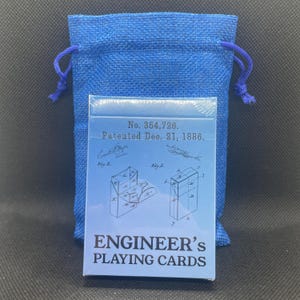 Unopened deck of cards resting in front of a blue drawstring baggy.