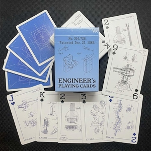 May include: A deck of "Engineer's Playing Cards" with a light blue box featuring patent illustrations. The cards have a blueprint design on the back and patent drawings on the faces. The deck includes a variety of card suits and numbers.