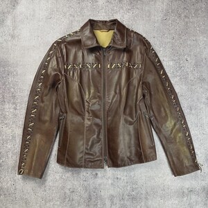 May include: A brown leather jacket with a zip-up front and a collared neckline. The jacket features decorative stitching along the sleeves and front, with a light-colored thread. The jacket is a medium size.