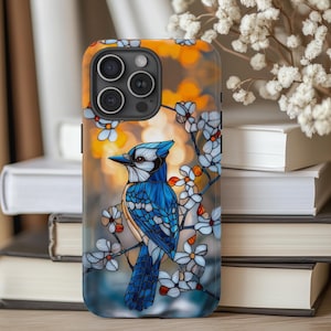 May include: A blue jay bird with stained glass-like design perched on a branch with white flowers. The background is a blurred sunset with orange and yellow hues. The image is printed on a black phone case.