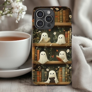 Pode incluir: Capa de telefone com um design fantasioso de uma estante com livros e figuras de fantasmas brancos lendo. A capa tem um fundo marrom escuro com detalhes florais e borboletas, e um recorte para a câmera.