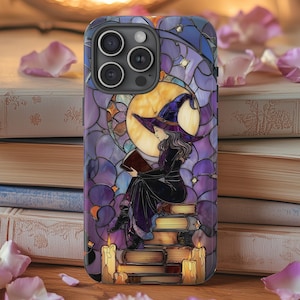 May include: A phone case featuring a stained-glass design of a witch reading. The witch is seated on a stack of books, wearing a purple hat and dress. The background includes a moon, stars, and candles, with a color palette of purple, blue, and gold.