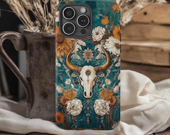 May include: A teal phone case featuring a detailed design of a steer skull with long horns, surrounded by orange and white flowers. The case has a floral pattern and a dark background.