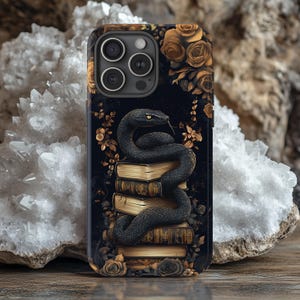 May include: A black snake coiled around a stack of antique, leather-bound books with gold detailing. The snake is set against a black background with gold flowers and foliage. The image is on a phone case.