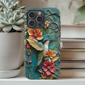 Könnte beinhalten: Eine blaugrüne Handyhülle mit einem Kolibri- und Blumendesign. Der Kolibri ist grün, blau und gelb mit einem langen Schnabel. Die Blumen sind rosa, gelb und orange. Die Hülle hat ein erhabenes, strukturiertes Design.