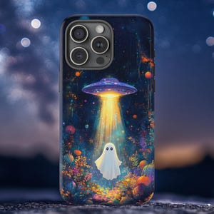 Op de afbeelding: Telefoonhoesje met een Halloween-thema. Een paarse en blauwe UFO straalt helder licht op een spook. De achtergrond toont een sterrennacht met kleurrijke planten en pompoenen. De hoes heeft een donkerblauwe rand.