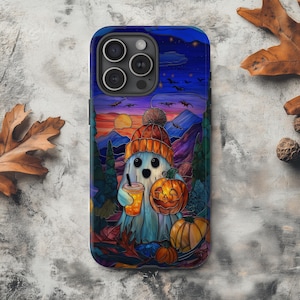 Peut inclure: Coque de téléphone avec un fantôme de dessin animé portant un bonnet orange, tenant une boisson et une citrouille sculptée. Le fond représente un coucher de soleil sur des montagnes, avec des chauves-souris dans le ciel. Design coloré de style vitrail.