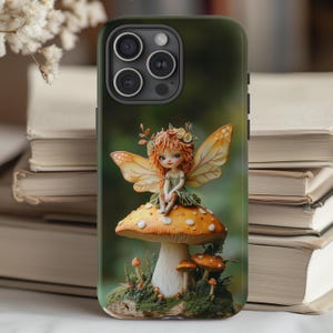 May include: A phone case with a whimsical design featuring a fairy sitting on a mushroom. The fairy has brown hair, a green dress, and wings. The mushroom is brown and white with a green base.