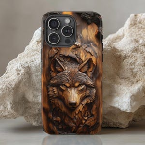 Può includere: Una custodia per telefono marrone e nera con un design a lupo in legno intagliato. Il viso del lupo è prominente e dettagliato, con un'espressione realistica.