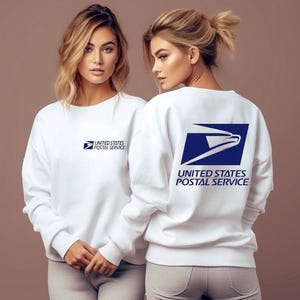Può includere: Felpa bianca con il logo del United States Postal Service. Il logo anteriore è piccolo, mentre il logo posteriore è un grande quadrato blu con un'aquila bianca e testo.