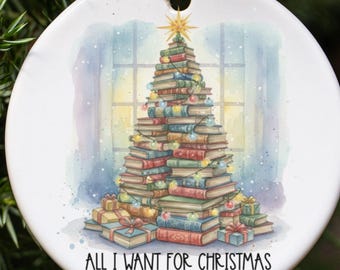 May include: A white ceramic Christmas ornament with a gold string. The ornament features a watercolor illustration of a Christmas tree made of books, topped with a star. The text "ALL I WANT FOR CHRISTMAS" is at the bottom.