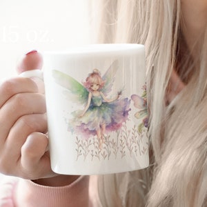 May include: White ceramic mug with a watercolor illustration of a fairy with green wings and a purple dress. The fairy is surrounded by flowers and greenery.