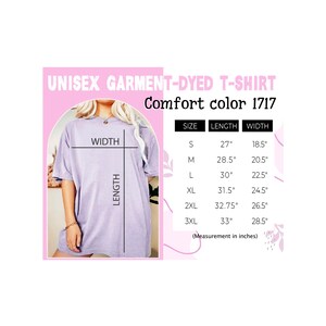 K&ouml;nnte beinhalten: Ein Unisex-T-Shirt aus gef&auml;rbtem Stoff in helllila. Das T-Shirt wird an einem Model gezeigt und hat eine Gr&ouml;&szlig;entabelle mit Ma&szlig;en in Zoll.