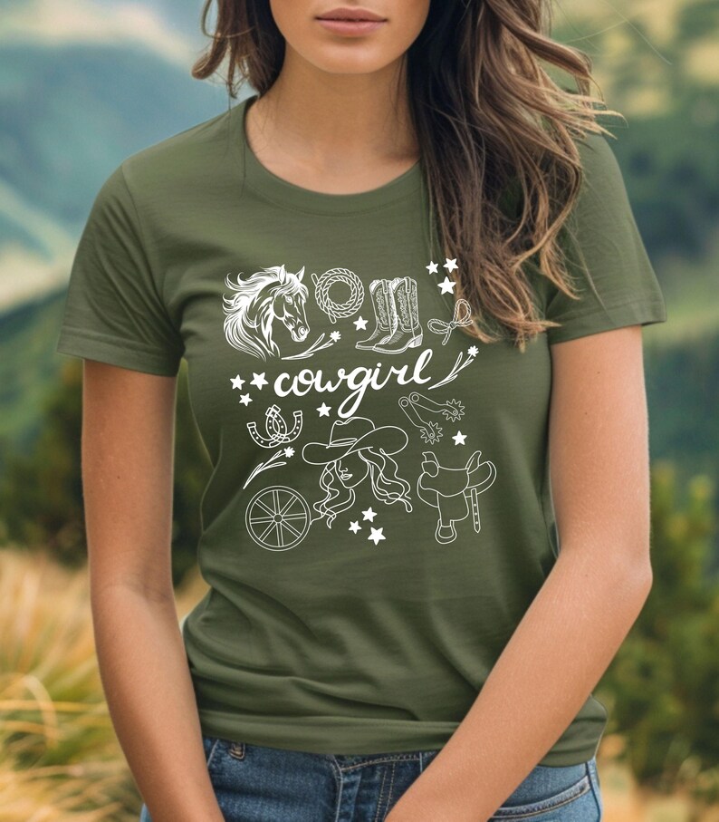K&ouml;nnte beinhalten: Ein gr&uuml;nes T-Shirt mit einem wei&szlig;en Grafikdesign einer Cowgirl mit einem Pferd, Stiefeln, Sternen und anderen Western-Motiven. Der Text "cowgirl" ist im Design enthalten.
