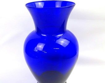 May include: A cobalt blue glass vase with a rounded body and a flared opening. The vase has a smooth, glossy finish.